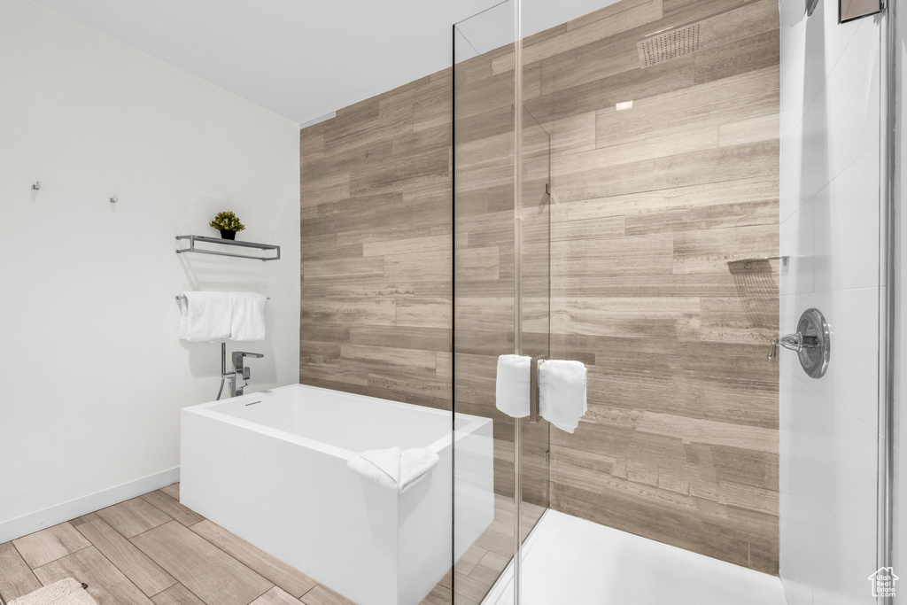 Bathroom with a freestanding bath, a shower stall, and wood finished floors