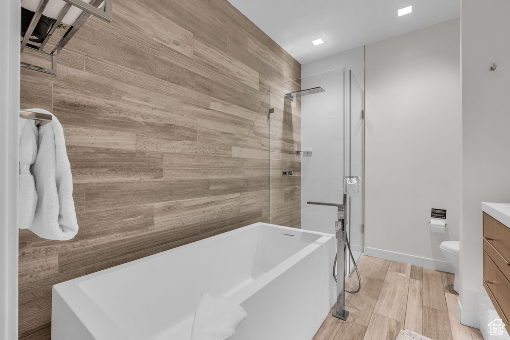 Bathroom featuring a freestanding bath, vanity, a tile shower, and wood finished floors
