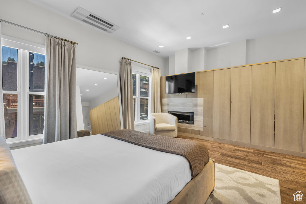 Bedroom with wood finished floors, a fireplace, and recessed lighting