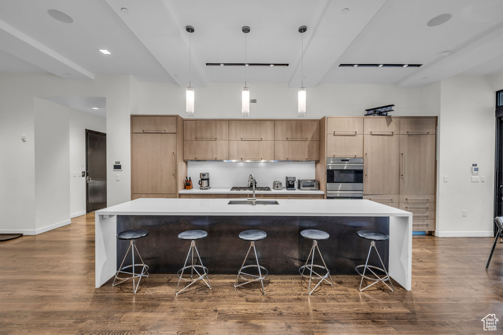 Kitchen featuring modern cabinets, dark wood finished floors, decorative backsplash, a spacious island, and beamed ceiling