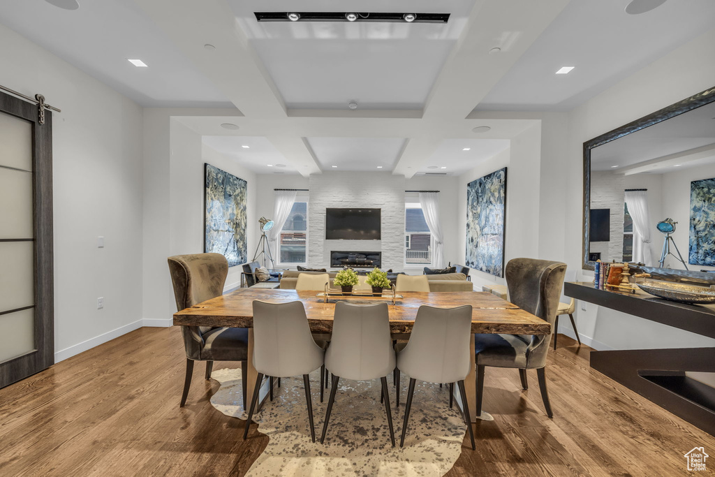 Dining area featuring wood finished floors, a large fireplace, beam ceiling, recessed lighting, and coffered ceiling