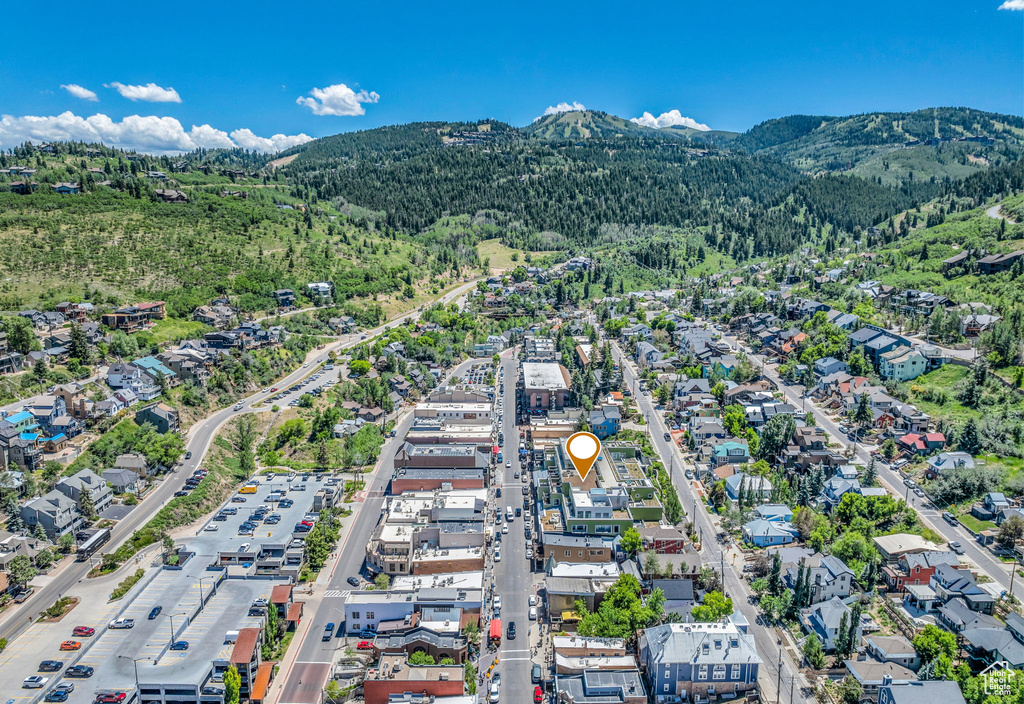 Aerial view of property and surrounding area featuring a mountainous background and a forest