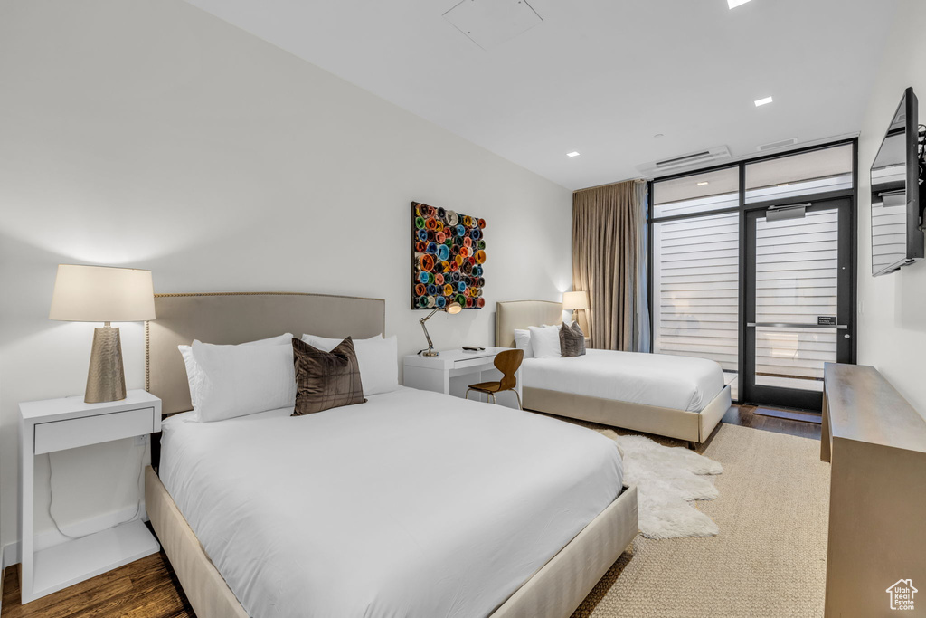 Bedroom featuring access to exterior, wood finished floors, a wall of windows, and recessed lighting