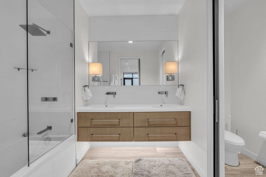Full bathroom with wood finished floors, shower / bath combination, and double vanity