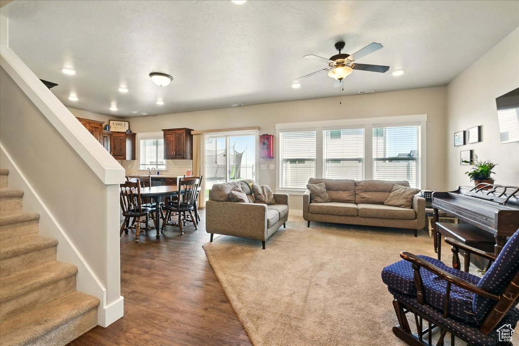 Living area with a ceiling fan, wood finished floors, stairway, and recessed lighting
