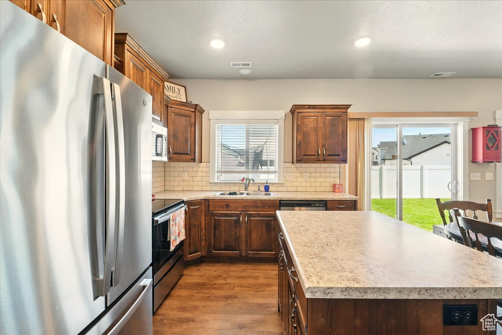 Kitchen with appliances with stainless steel finishes, dark wood finished floors, backsplash, light countertops, and recessed lighting