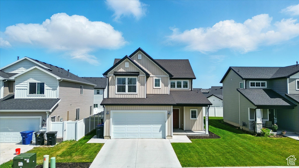 Craftsman house with board and batten siding, a garage, concrete driveway, and a residential view