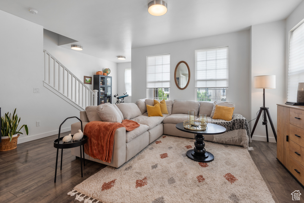 Living room featuring stairs, dark wood-style floors, and plenty of natural light