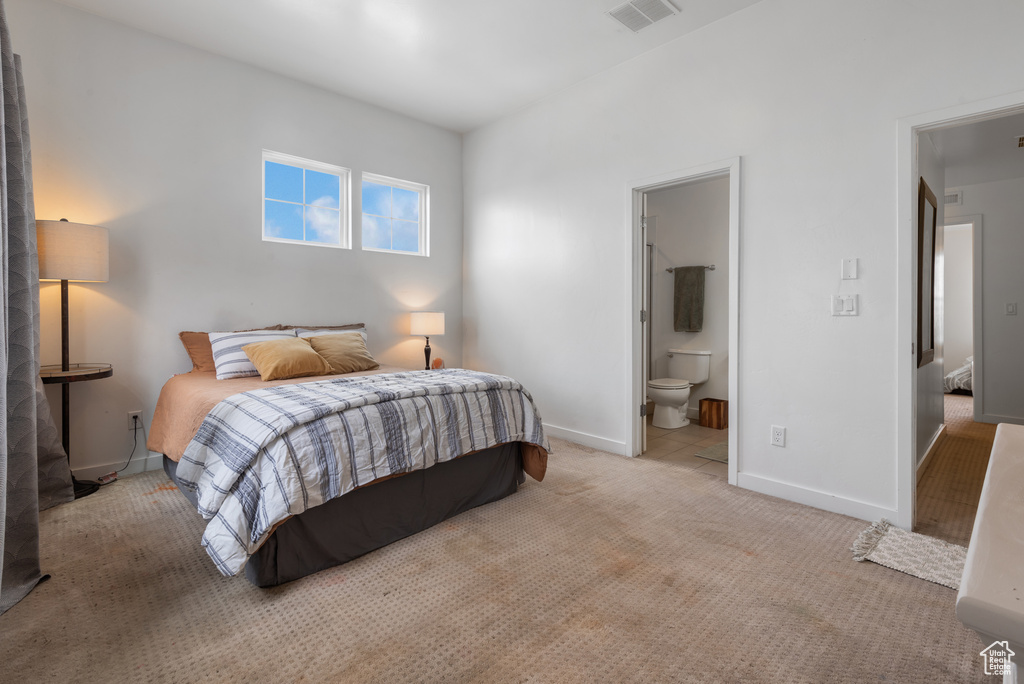 Carpeted bedroom featuring baseboards and ensuite bath
