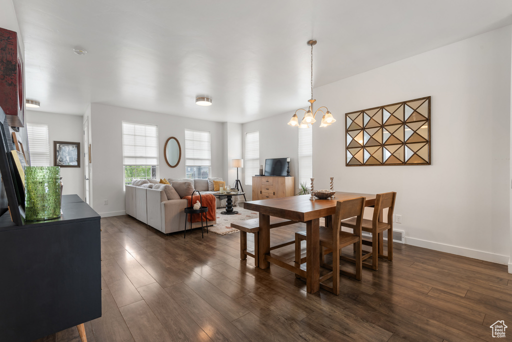 Dining space featuring dark wood-style flooring and a chandelier