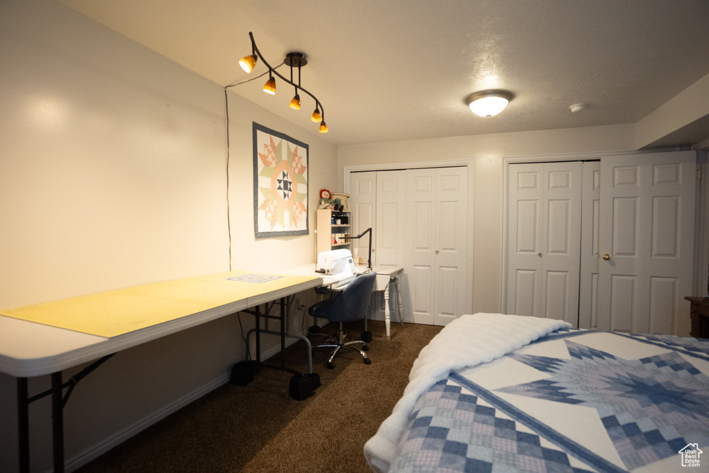 Bedroom featuring dark colored carpet, multiple closets, and built in study area