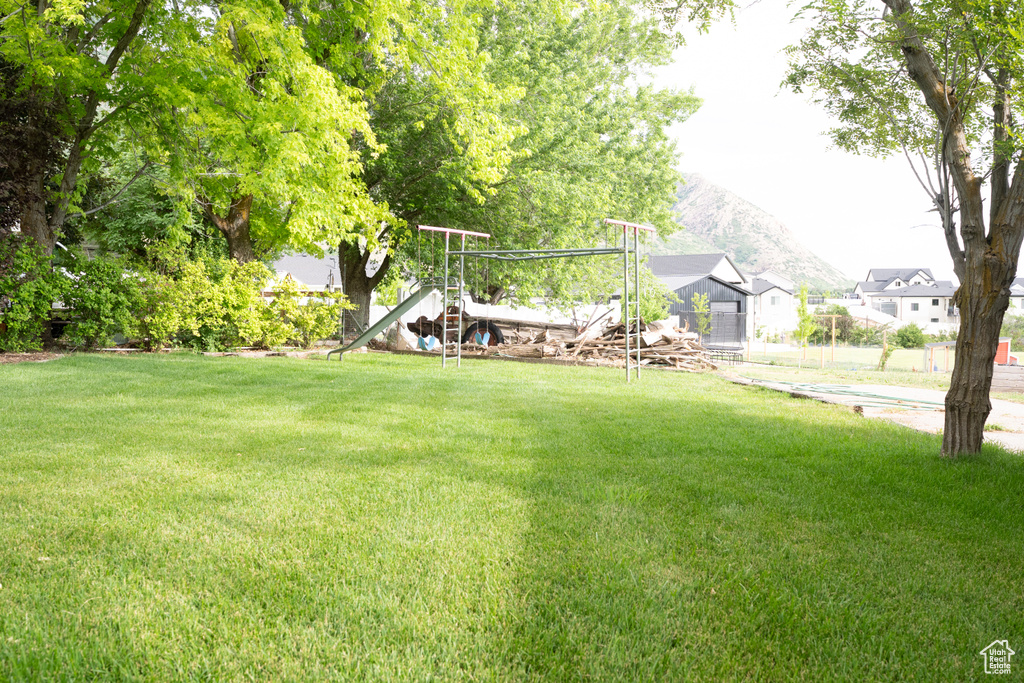 View of green lawn featuring a mountain view and a playground