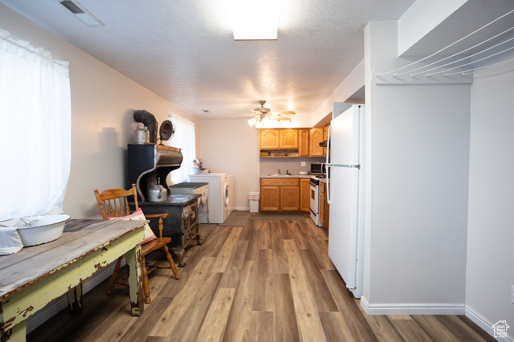 Kitchen featuring white appliances, a wood stove, light wood-style floors, light countertops, and ceiling fan