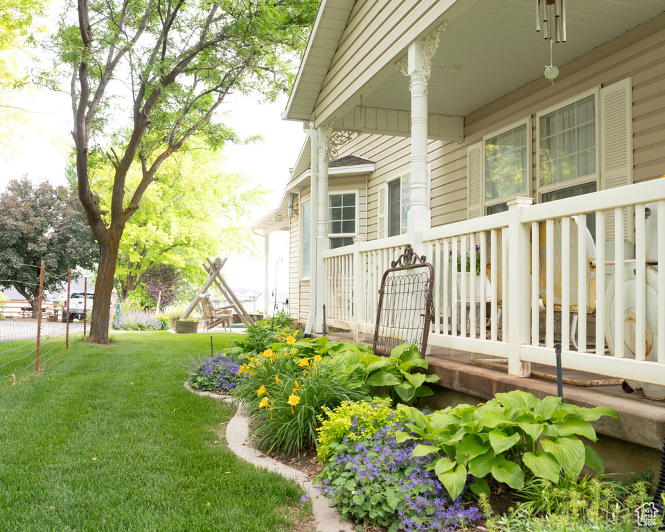 View of green lawn featuring covered porch