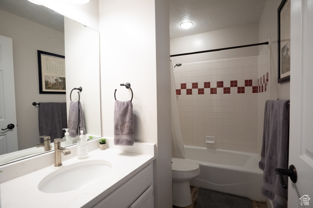 Full bathroom with vanity, shower / bath combination with curtain, and a textured ceiling