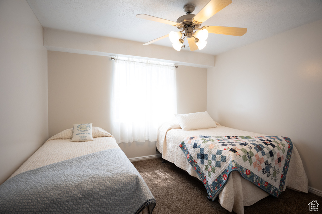 Bedroom with dark carpet and a ceiling fan