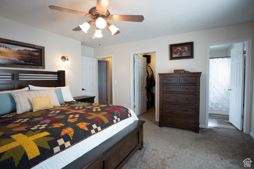 Bedroom with a walk in closet, light colored carpet, a closet, ensuite bath, and a ceiling fan