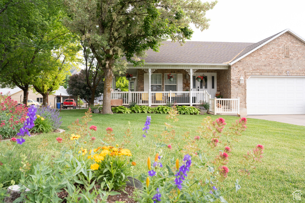 Ranch-style house with a porch, an attached garage, brick siding, a front yard, and driveway