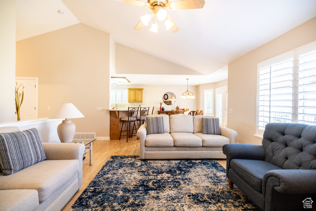 Living area with a ceiling fan, vaulted ceiling, and light wood-type flooring