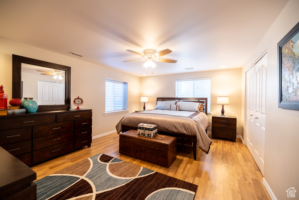Bedroom with light wood-type flooring, a ceiling fan, and a closet