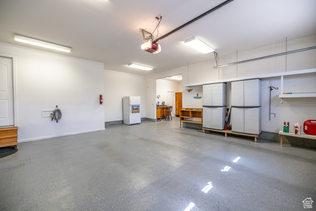 Garage with freestanding refrigerator and a garage door opener