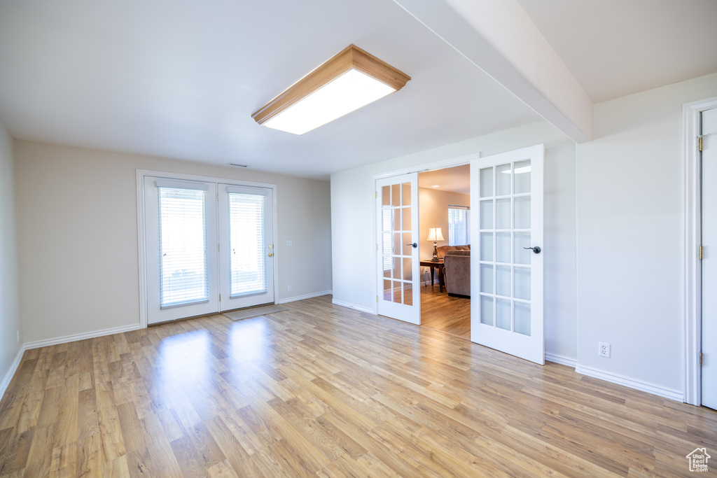 Unfurnished room with french doors and light wood-type flooring