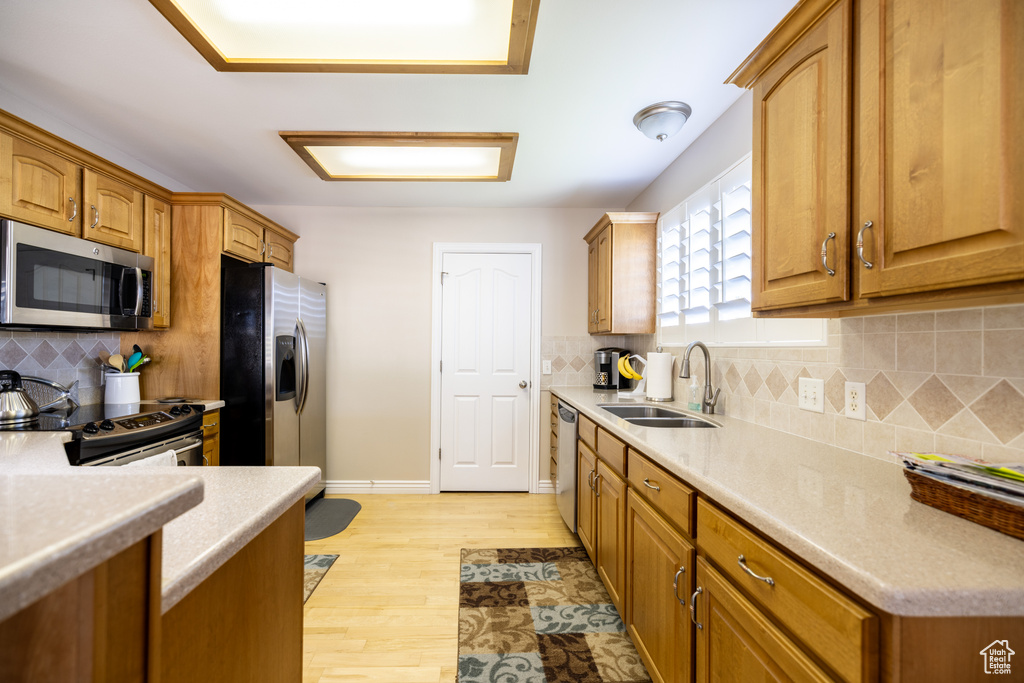 Kitchen with appliances with stainless steel finishes, decorative backsplash, light wood-type flooring, and light countertops