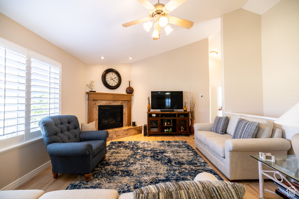 Living room featuring light wood-style floors, a fireplace, lofted ceiling, ceiling fan, and recessed lighting