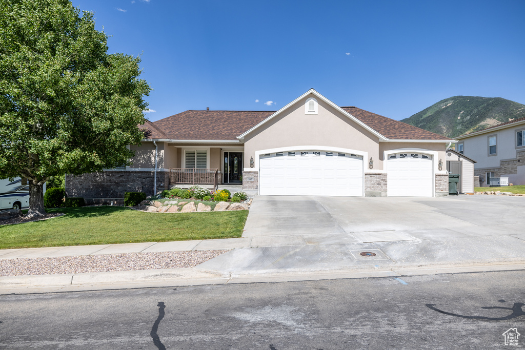 Single story home featuring stucco siding, an attached garage, a front yard, and driveway