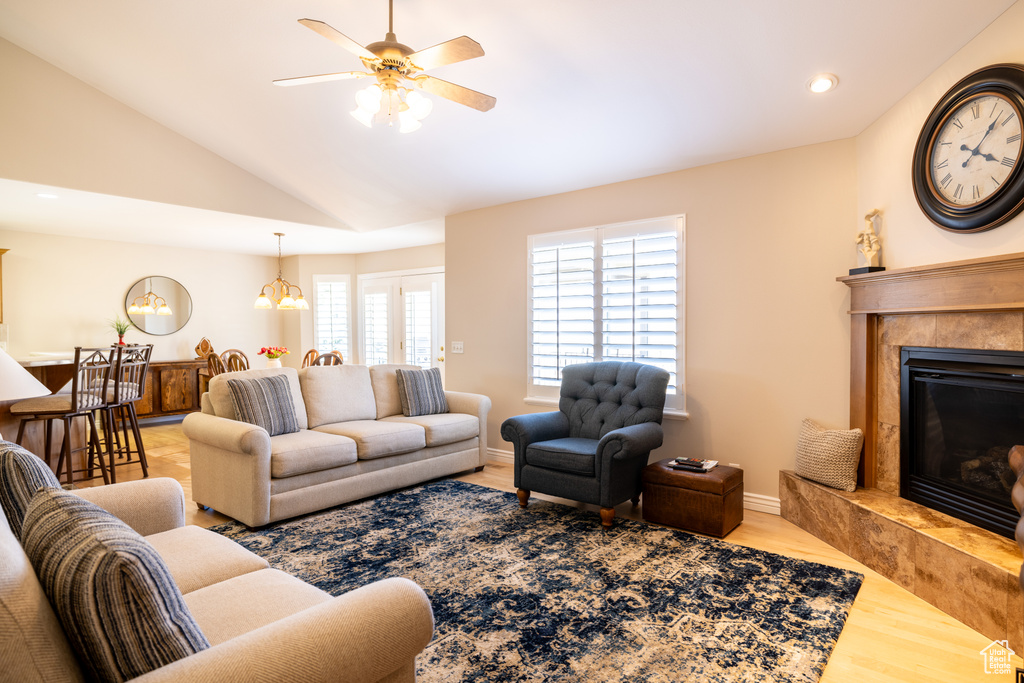 Living area with wood finished floors, vaulted ceiling, a ceiling fan, a high end fireplace, and recessed lighting