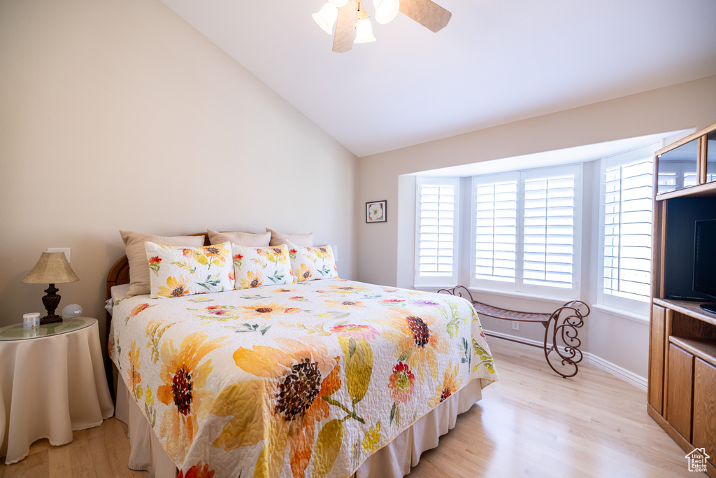 Bedroom with light wood-style flooring, multiple windows, vaulted ceiling, and a ceiling fan