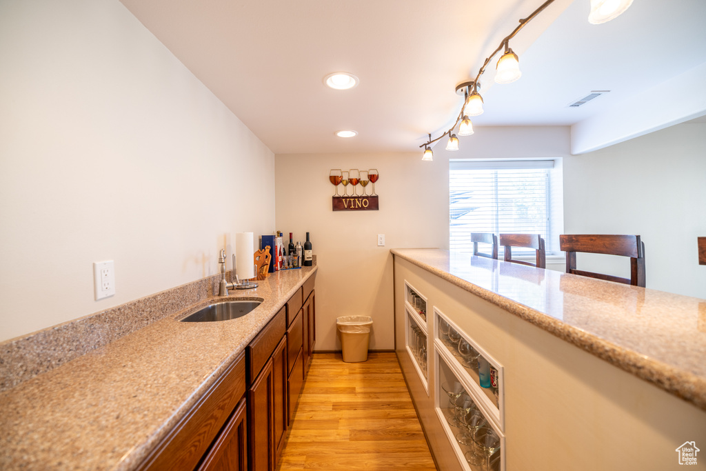 Kitchen featuring light wood-type flooring, recessed lighting, light stone countertops, and brown cabinetry