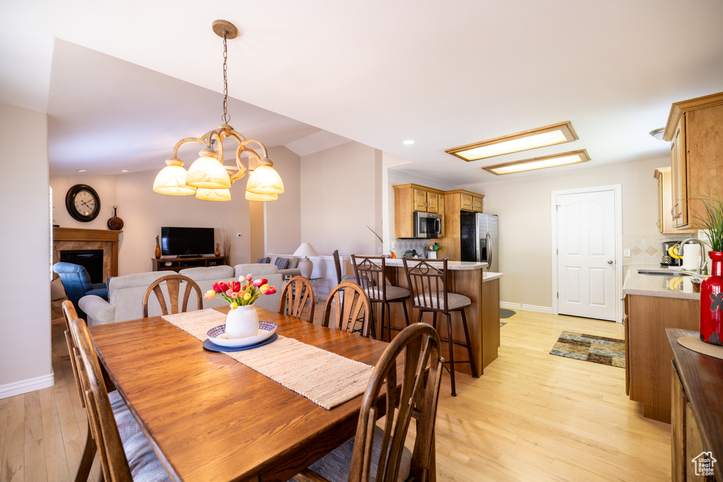 Dining room with light wood-type flooring, a fireplace, and recessed lighting