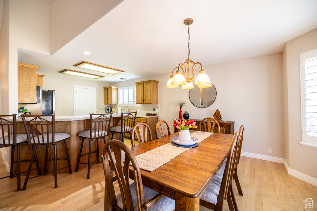 Dining space with light wood finished floors, a chandelier, and recessed lighting