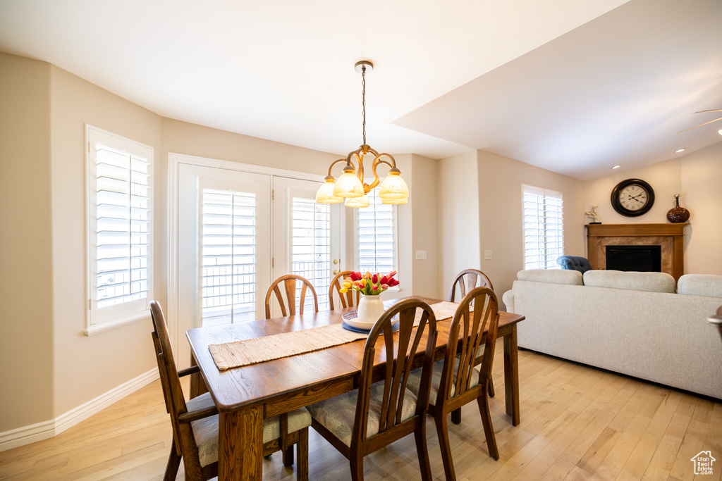 Dining room featuring a chandelier, light wood-style floors, and a premium fireplace