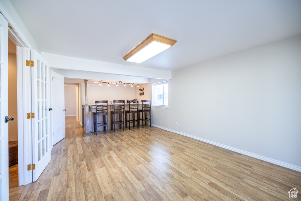 Unfurnished room featuring wood finished floors, bar, track lighting, and french doors