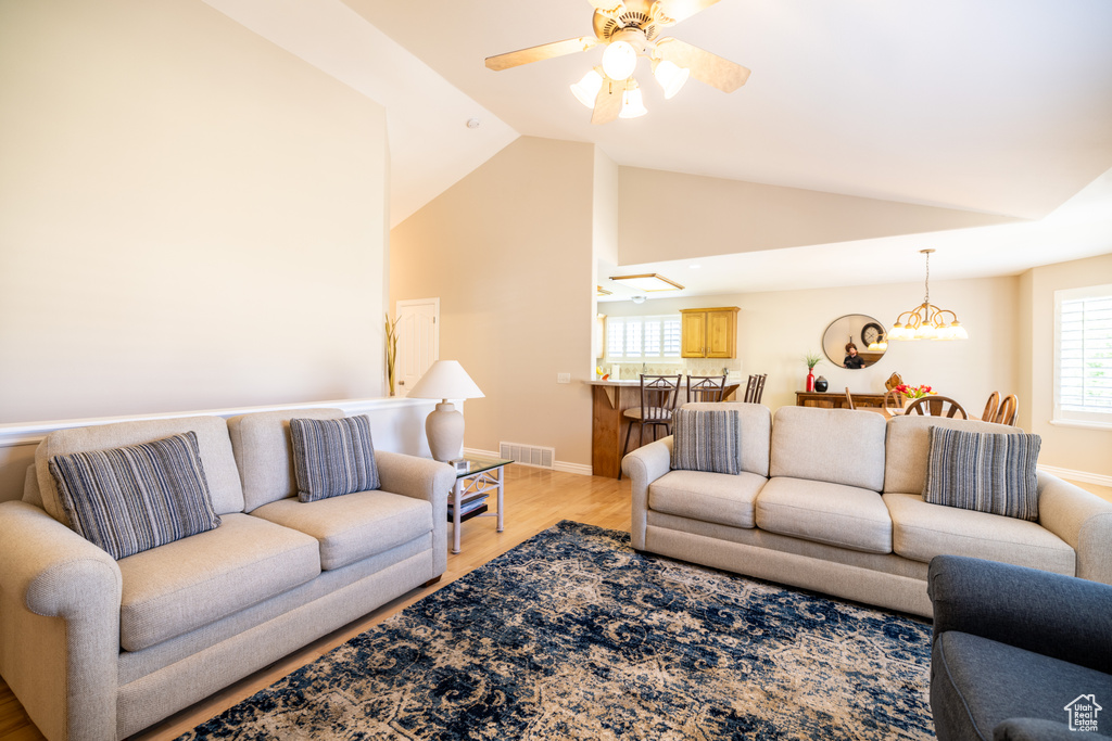 Living area featuring a ceiling fan, lofted ceiling, light wood-type flooring, and plenty of natural light