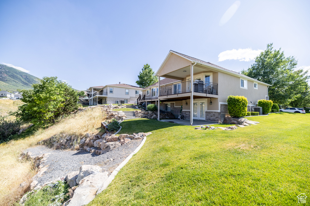 Rear view of property with french doors, a lawn, a deck, stucco siding, and a patio