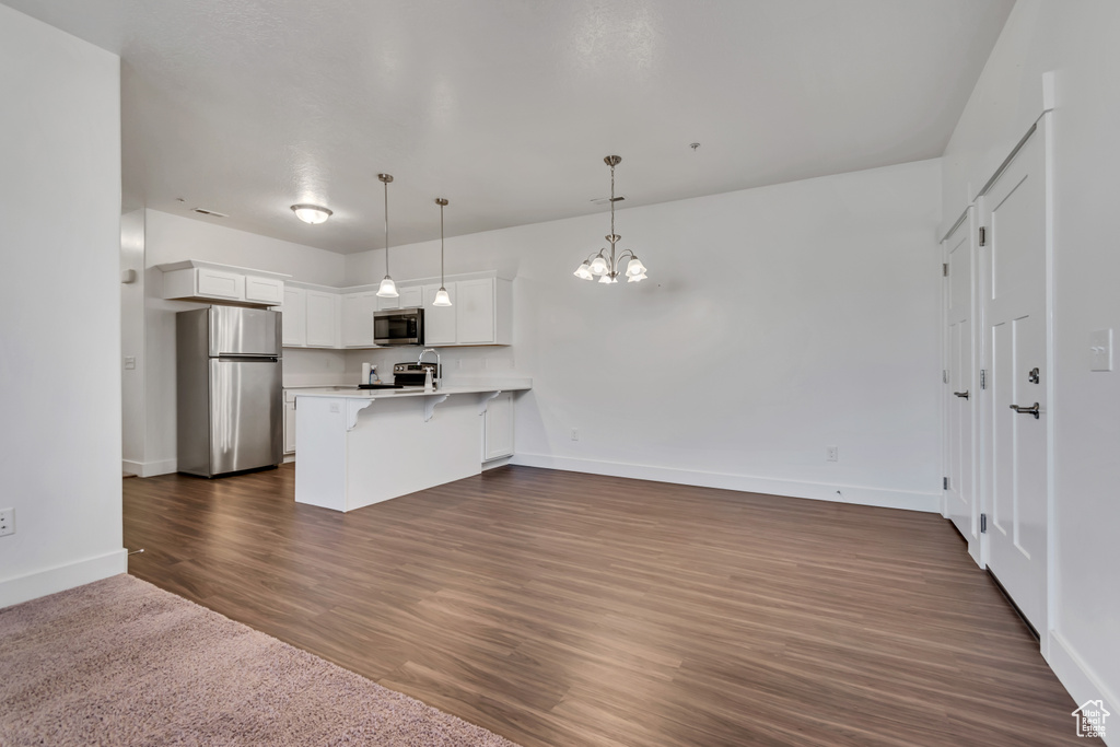Kitchen featuring appliances with stainless steel finishes, a peninsula, a kitchen bar, a chandelier, and open floor plan