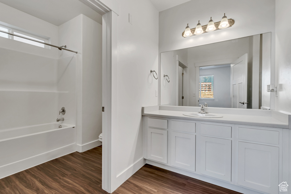Bathroom with washtub / shower combination, wood finished floors, and vanity
