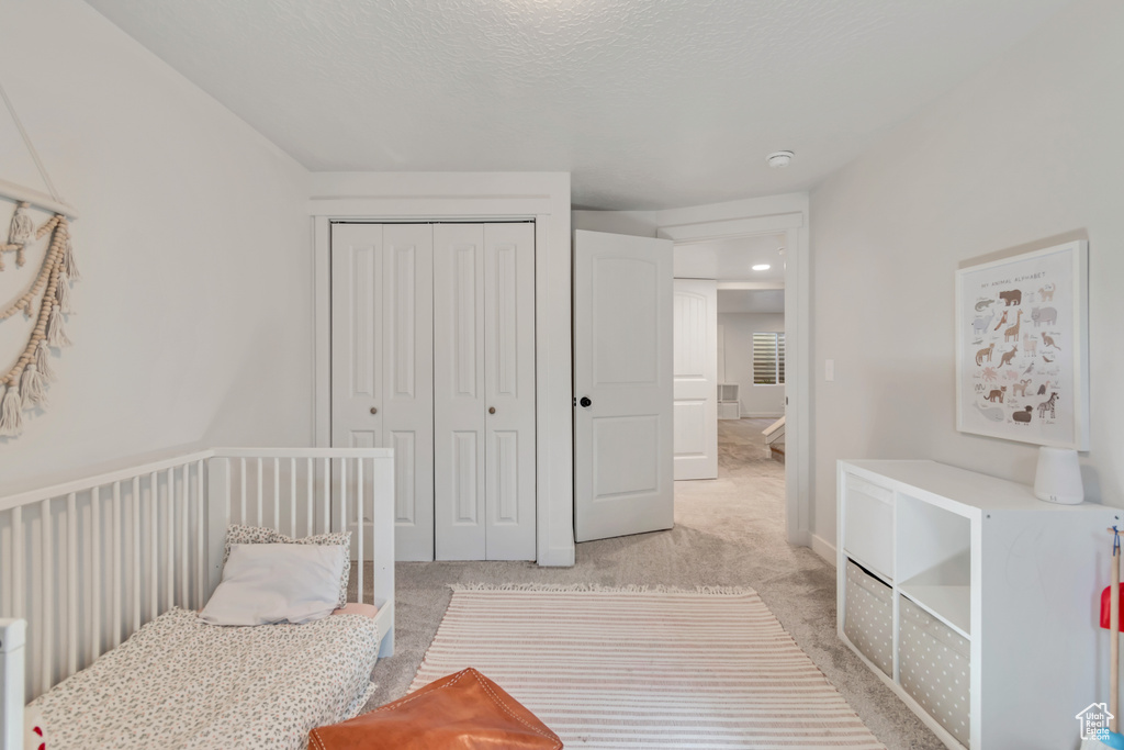 Bedroom featuring light colored carpet, a closet, and a textured ceiling