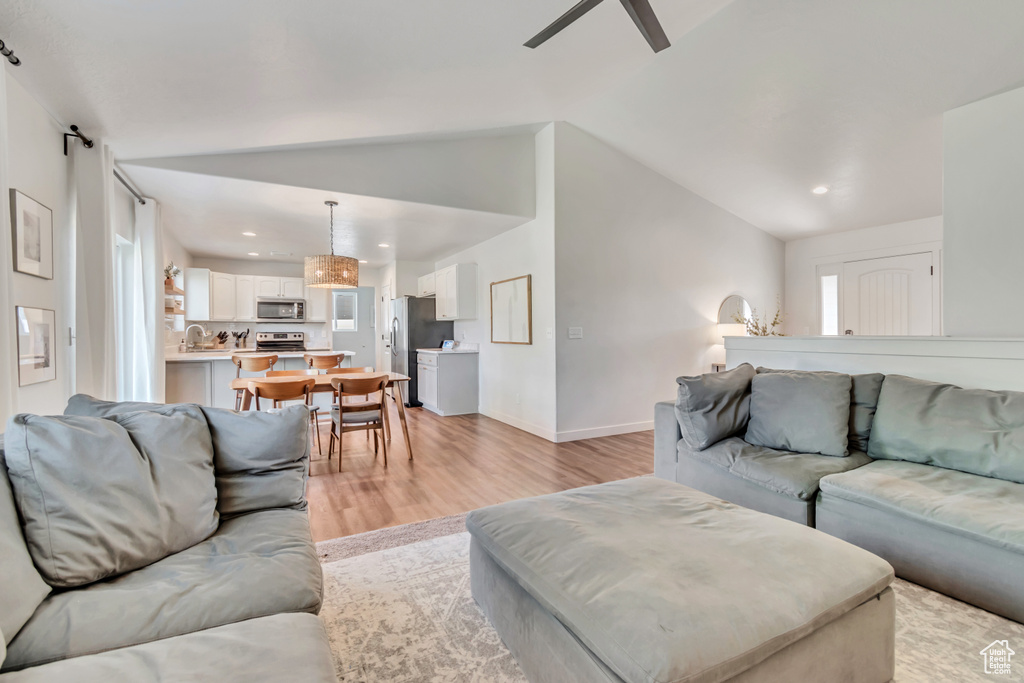 Living room featuring light wood-style flooring, ceiling fan, lofted ceiling, recessed lighting, and plenty of natural light