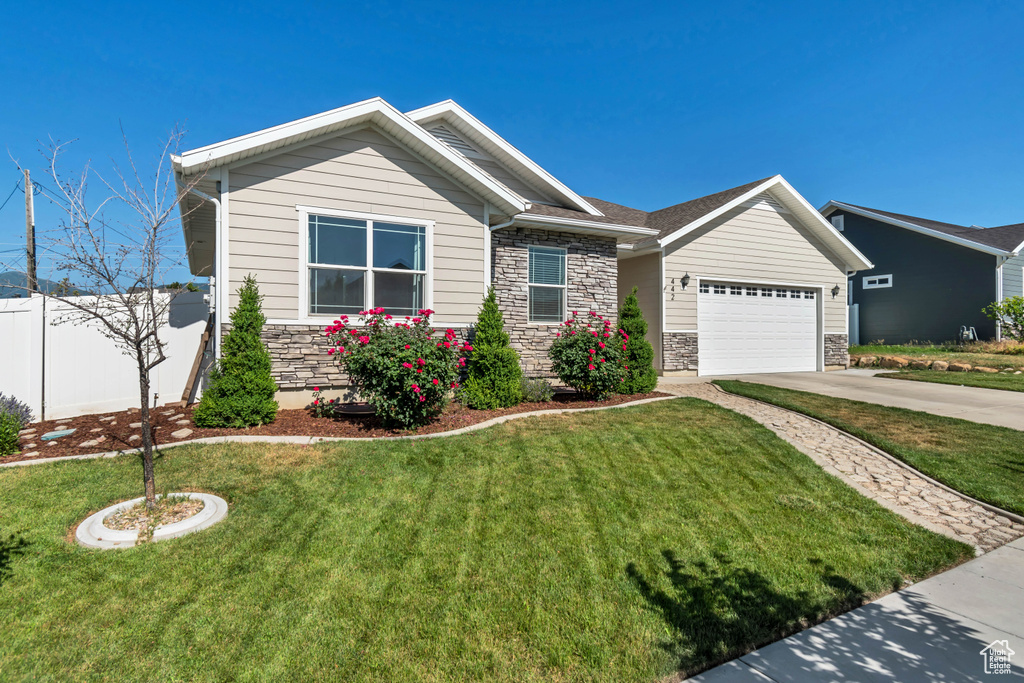 View of front of property featuring stone siding, concrete driveway, and a garage