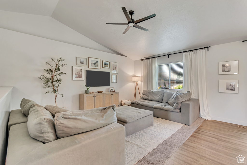 Living area with ceiling fan, lofted ceiling, and light wood-style flooring