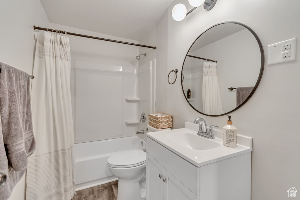 Full bath featuring vanity, shower / tub combo with curtain, and wood finished floors