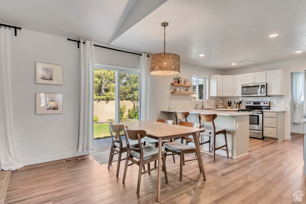 Dining room with recessed lighting, light wood finished floors, and a barn door