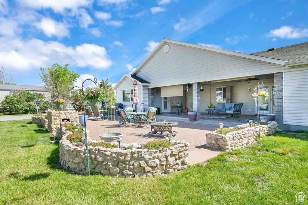 Rear view of property featuring an outdoor fire pit, a patio, and a yard