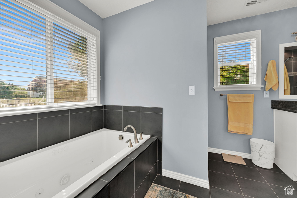 Bathroom with a tub with jets, tile patterned floors, and vanity