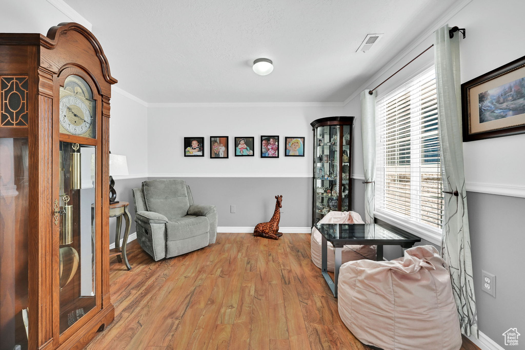 Living area with wood finished floors and crown molding