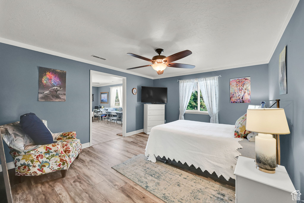 Bedroom featuring crown molding, wood finished floors, a ceiling fan, and a textured ceiling